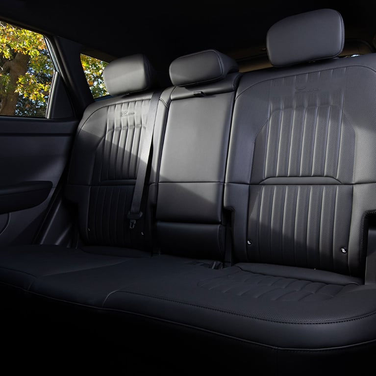 Interior view of the 2027 Kia Seltos SUV showing the roomy back row seating space in black, with headrests and comfortable seating for three.