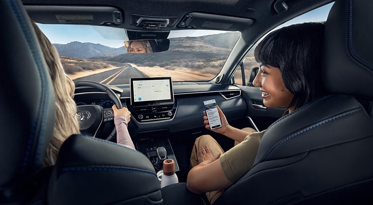 Two women in a Toyota talking and looking at devices